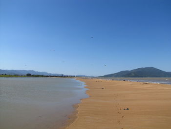 Scenic view of beach against clear blue sky