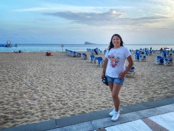 Portrait of woman standing at beach against sky