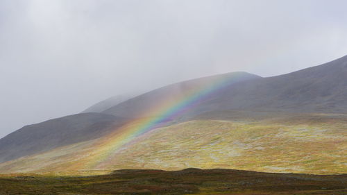 Scenic view of rainbow over mountain against sky