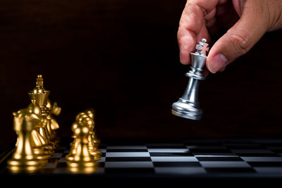 Cropped hand of person playing with chess against black background