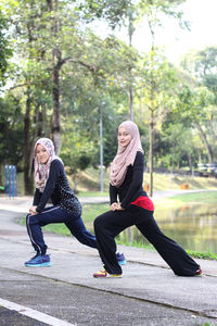 Sisters wearing hijab while exercising by lake at park