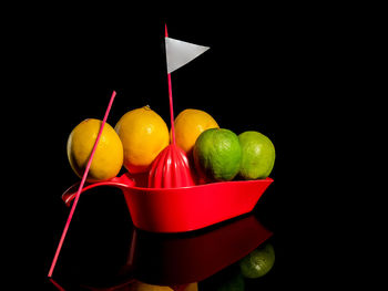 Creative still life with lemons and limes floating on a boat on a black background