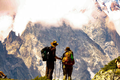 Rear view of hikers standing against mountains