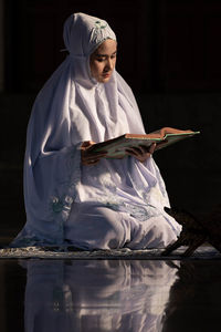 Young woman in hijab reading koran
