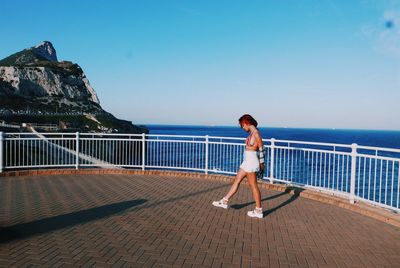 Woman standing on railing against sea