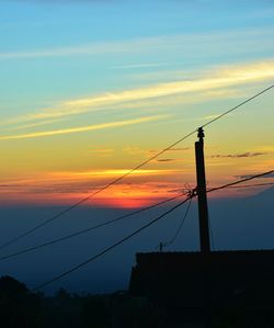 Low angle view of silhouette electricity pylon against sky during sunset