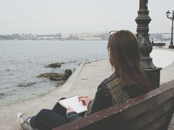 Rear view of woman sitting on retaining wall