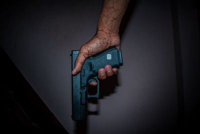 Digital composite image of hand holding gun against wall