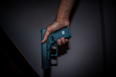 Close-up of hand holding camera against wall