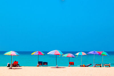 Umbrellas on beach against clear blue sky