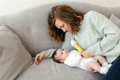 Happy mother resting on sofa with baby