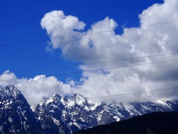 Low angle view of snowcapped mountains against blue sky