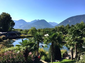 Scenic view of lake and mountains against clear blue sky