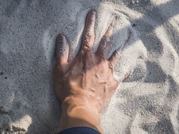 High angle view of hands on sand