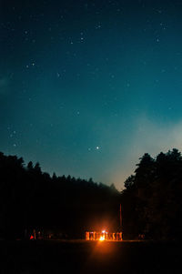 Large group of people standing around campfire at night