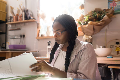 Woman with braided hair at her home office looking through the documents