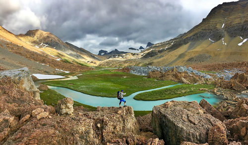 Athletic young man hiking by high mountain river in alberta, canada