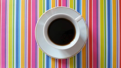 Directly above shot of black coffee on colorful patterned table