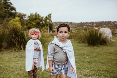 Boys wearing capes standing on meadow