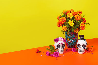 Close-up of flower vase on table against yellow background