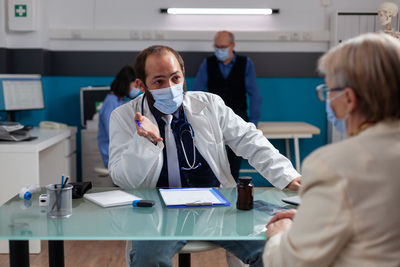 Doctor wearing mask examining patient in clinic