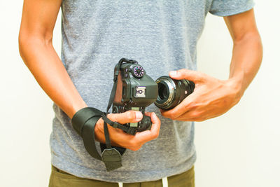 Midsection of man holding camera against white background