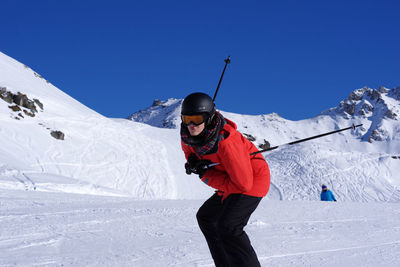 Woman standing on snowcapped mountain against sky