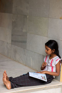 Girl reading book while sitting on floor