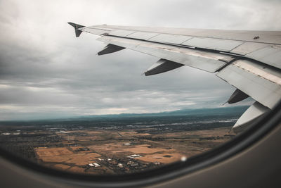 Aerial view of aircraft wing over landscape against sky