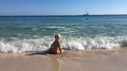 Woman standing on beach by sea against sky