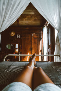 Low section of woman relaxing on bed