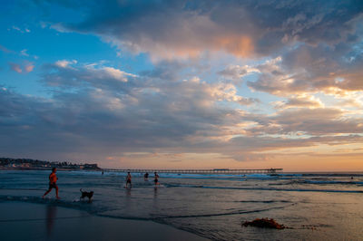 People on beach against sky during sunset