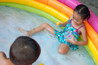 High angle view of siblings playing in wading pool