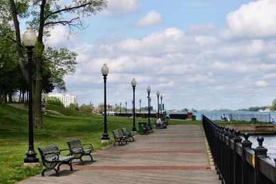 Benches on walkway by lake at park