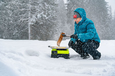 Person cooking pork ribs on camping stove in snow by the winter forest