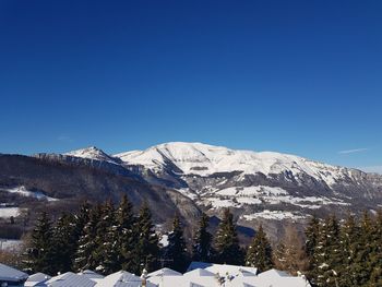 Scenic view of snowcapped mountains against clear blue sky