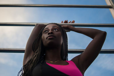 Portrait of young woman looking up against sky