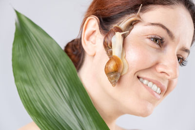 Close-up of smiling young woman with snail of face