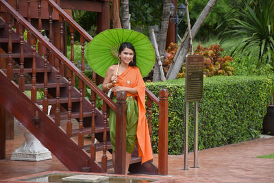 Smiling woman in traditional clothing standing outside temple