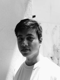 Portrait of young man standing against wall at home