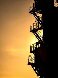 Low angle view of silhouette crane against sky during sunset