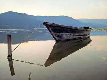 Boat moored on lake against sky