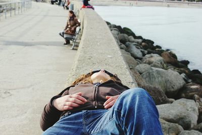 Woman lying on retaining wall by sea