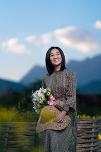 Portrait of smiling woman standing against blue sky