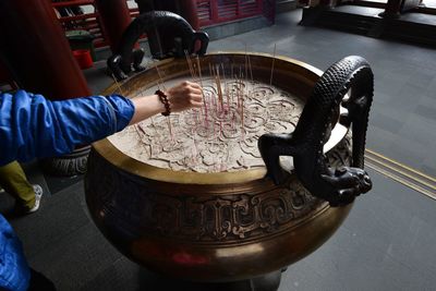 Cropped hand of person holding incense in temple