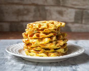 Stack of vegetable waffles on white plate in rustic kitchen close up