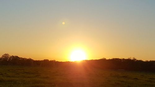 Scenic view of field against clear sky during sunset