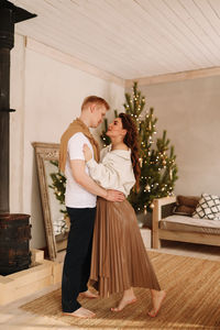 A man and a woman in love embrace give gift gifts celebrate a holiday at the christmas tree at home