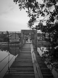 Wooden bridge over calm sea against sky
