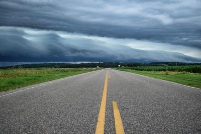 Road passing through landscape against cloudy sky